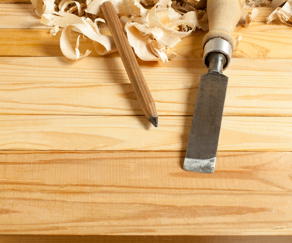 Handcrafted children's furniture detail—chisel, pencil, and wood shavings on pine