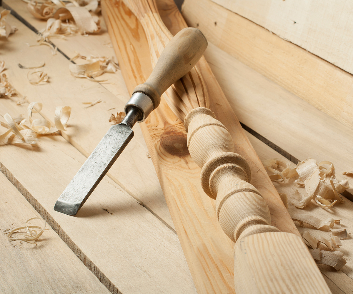 Handcrafted dining room furniture detail—chisel, shavings, and turned table leg.