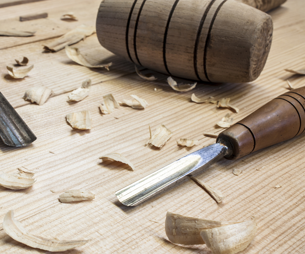 Wood chisel and mallet with fresh shavings on a planed board.