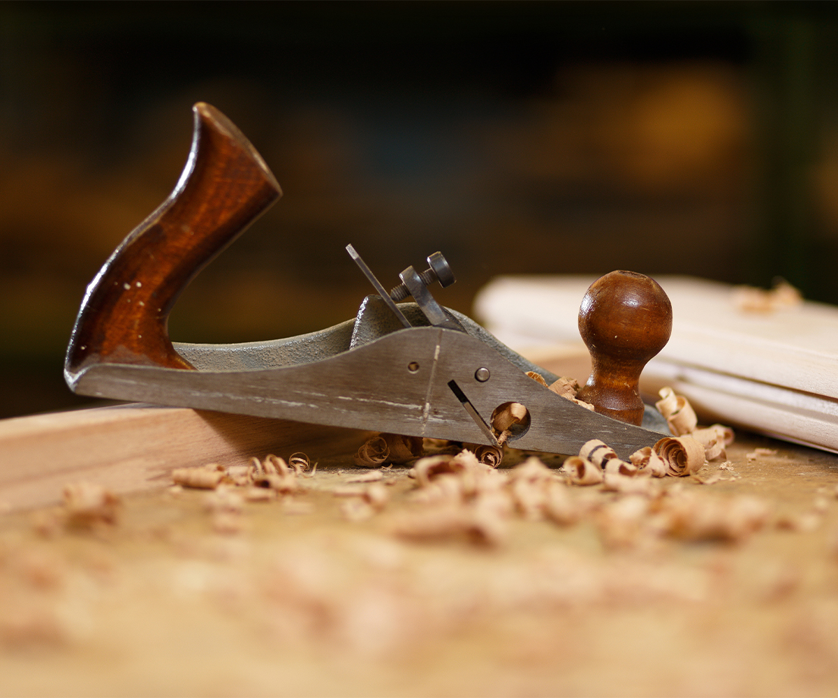 Office furniture craftsmanship—hand plane shaving hardwood on a workbench