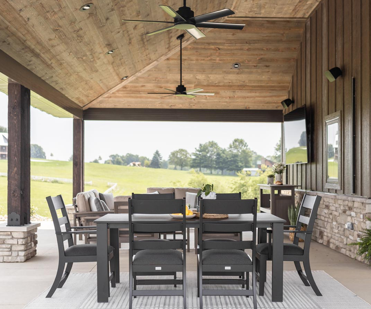 Sculptural trestle table with eight chairs—solid wood dining room furniture on plush rug.
